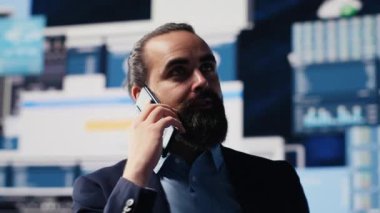 Profesyonel işadamı, şirketin performansını ve sezgilerini değerlendirmek için KPI metrikleriyle çevrili bir telefona cevap veriyor. İşini geliştirmek için uzaktan iletişimi kullanıyor, büyüklük. Kamera A.