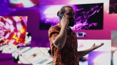 Sanatçı ve DJ, canlı neon ışıklar altında, gece hayatı atmosferinde müzik kültürü, görseller ve sosyal medya ya da yayın için kentsel ortam ile telefon görüşmelerine cevap veriyor. Havalı yaratıcı adam. Kamera A.