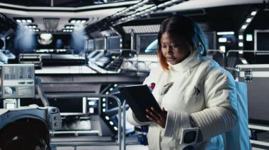Yabancı gezegendeki yüzey görevini tamamladıktan sonra uzay istasyonu analizlerini kontrol etmek için tablet kullanan kadın astronot. Kadın navigasyon koordinatlarını giriyor, Dünya 'ya dönmeye hazırlanıyor, kamera A