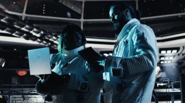 Astronot yörünge yolunu gösteren arayüze bakıyor, uzay görevi sırasında iş arkadaşıyla sohbet ediyor. Takım çalışması kozmonotlar, insanoğlunun hayatta kalma mücadelesi sırasında sorun çıkaran donanım, kamera B