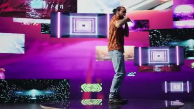 Müzik etkeni parti sahnesinde dans ederken neon ışıklarıyla renkli siber punk tarzını ifade ediyor. Vuruşlar ve sanatsal görseller kentsel yaratıcılığı gösteriyor. Kamera B.