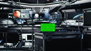 Yakındaki monitörün yanındaki fütüristik uzay aracı hangarında Mars 'ın kontrol paneli telemetrisini gösteren yeşil ekran dizüstü bilgisayar. Yörünge görevi sırasında Kızıl Gezegen 'e gitmek için kullanılan model defter.