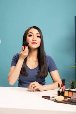 Çevrimiçi makyaj kursuna ev sahipliği yapan, çeşitli fırça teknikleri sergileyen sıcak ve çekici güzellik uzmanı. Asyalı içerik yaratıcısı stüdyosundan yayın yapıyor, kozmetik aletleri tartışıyor..