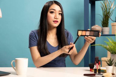 Asyalı güzellik etkileyicisi canlı yayında kozmetik ürünleri sunarak abonelerine eleştiriler sunuyor. Genç kadın video blogundaki en son göz farı renk paletini tartışıyor..