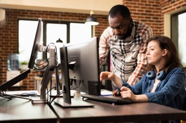 Siyahi adam tasarım sürecini sunan beyaz kadını dikkatle dinlerken, çeşitli iş arkadaşları tartışmaya başladı. Bir girişim projesinde bilgisayar kullanan ve işbirliği yapan yaratıcı iş ortakları.
