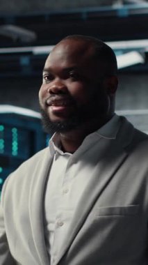 Sunucu merkezindeki gülümseyen mühendis, bileşenler arasında veri merkezi enerji tüketimini izliyor. Veri merkezinde yürüyen mutlu bilişim uzmanı, sondaj sensörlerinin en uygun şekilde çalıştığından emin oluyor.