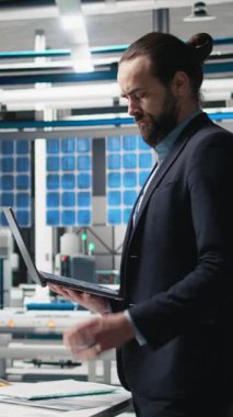 Resmi kıyafetli dikey video mühendisi danışmanı endüstriyel operasyonları inceliyor, iş uzmanlığı ve güneş teknolojisi üretim tesisinde verimliliği birleştiriyor. Alternatif enerji. Kamera A.