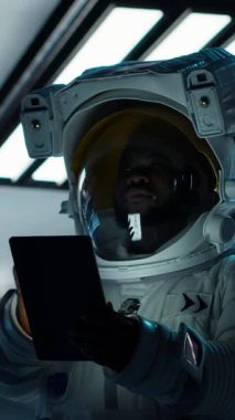 Dikey Kozmonot görüntüsü tablet üzerindeki navigasyon koordinatlarını doğruluyor, dışarıdaki gezegen görevine hazırlanıyor. Astronot güneş sistemine iniş işlemlerine başlamadan önce güvenlik kontrolü yapıyor.