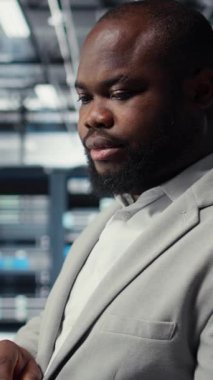 Bilgisayar kullanarak, güvenlik yamalarını çalıştırarak, güvenlik duvarı yapılandırmalarını doğrulayarak sunucu odasındaki mühendislerin dikey görüntülerini kapat. İşçi, veri merkezinde ekipman hassasiyeti taraması yapıyor. Kamera A.