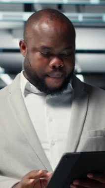 Veritabanında yürüyen teknisyenlerin sistem istikrarını kontrol etmek için tablet kullandıkları dikey video. IT uzmanı sunucu çiftliğini denetliyor, donanımları ayarlamak için aygıt kullanıyor, optimize ediyor