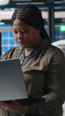 Fabrikadaki bir siyah teknisyenin dikey video portresi güneş panelleri üretim hattını denetleyerek üretim sürecinin denetlenmesini sağlar. Temiz enerji ve sürdürülebilirlik hedeflerine ulaşmak