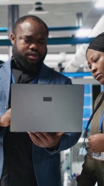 Dikey Video Afrikalı Amerikalı endüstriyel iş arkadaşları güneş panelleri için üretim hattı üzerinde takım çalışması yapıyorlar, teknik içgörü ve takım çalışmasını birleştirerek temiz enerji altyapısını ileriye taşıyorlar. Kamera B