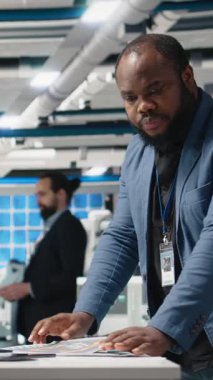 Dikey Video Afrikalı Amerikalı endüstriyel uzmanlar, güneş panellerini kağıt üzerinde modellerle inceliyor, sürdürülebilirliği ve yenilenebilir enerjiyi ve modern fabrikayı garanti altına almak için önemli içgörü okuyor.