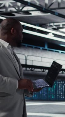 Dikey video Neşeli Veri Merkezi Sistem Yöneticisi otomatik betikler için kodu gözden geçirir. Jolly sunucu odası çalışanı ekipman üzerinde tanılama yapıyor, öngörü hatası algılaması yapıyor, kamera A