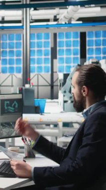 Dikey video erkek endüstriyel uzman modern ekipman ve performans ölçümleri ile yüksek teknoloji üretim hattını izliyor, temiz enerji üretim operasyonları. Genç iş analisti mühendis. Kamera.