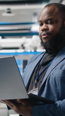 Bir güneş panelindeki dikey video Afrikalı Amerikalı yönetmen performans ve verimlilik ölçümlerini izliyor, liderliği gerçek zamanlı kalite kontrolü ve stratejik iş dünyasıyla birleştiriyor