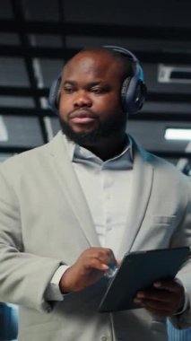 Dar geçitleri tanımlamak için tablet kullanan, kulaklık takan dikey video veri merkezi yöneticisi. Sunucu çiftliği bilişim uzmanı, sorun yaratan hataları dinlerken müzik dinliyor, iyileştirmeler yapılıyor, kamera B