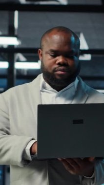 Dikey video veri merkezi mühendisi ekipman performansını analiz ediyor, teknik sorunları çözüyor. Sunucu çiftlik çalışanı iş görevleri yapıyor, işlemleri denetliyor, verimlilik optimizasyonlarını uyguluyor