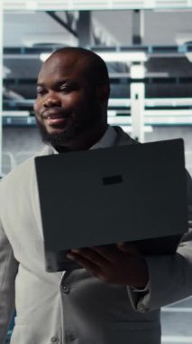 Veri merkezinde yürüyen dikey video teknisyeni, yapay zeka iş yüklerinde en az gecikme için depolama cihazlarını yapılandırıyor. Afrikalı Amerikalı çalışan, sunucu çiftliğinde sinirsel ağlar kurmak için aygıt kullanıyor.