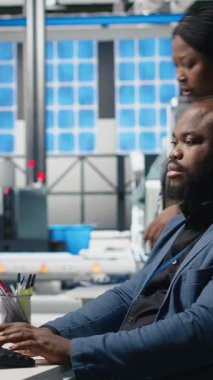 Bir güneş paneli enerji santralinde işbirliği yapan, temiz enerji üretimi ve sürdürülebilirliği sağlamak için planlar ve üretim hattı metriklerini inceleyen çok ırklı uzmanlardan oluşan dikey video ekibi. Kamera.