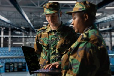 Sunucu merkezinde takım çalışması yapan askerler beyin fırtınası yapıyor, laptoptan raporları kontrol ediyorlar. Ordu bilgi uzmanlarından oluşan bir ekip veri merkezindeki not defterini kullanarak birlikte çalışıyor, sistemleri izliyor.