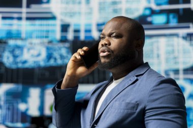 Siyah teknoloji uzmanı yapay zeka destekli bir ortamda akıllı bir telefonla konuşuyor, öngörücü algoritmaları ve makine öğrenme sistemlerini temsil ediyor. Otomasyon ve yenilik üzerine çalışmak.