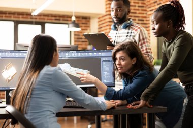 Genç çoklu etnik teknisyenler üretim endüstrisi için bir prototip tasarlıyorlar. Çeşitli mühendisler CAD yazılımı kullanarak bir mekanik klemp geliştirerek masa etrafında işbirliği yapıyor..