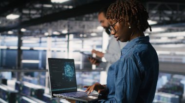 Veri merkezindeki sistem yöneticileri AI LLM görüntülemesini izliyor. Afrika kökenli Amerikan sunucu çiftliği çalışanları, makine öğrenme sürecine güç veren platformları denetliyor.