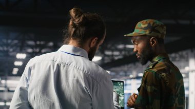 Askeri teknisyen güvenli sunucu merkezinde dizüstü bilgisayardaki taktik gösterge panelini inceliyor. Not defterinde stratejik iletişim ve altyapı denetim yazılımı kullanan ordu uzmanı