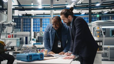 Çok ırklı mühendisler, güneş panelleri için üretim hattı üzerinde takım çalışması yapan endüstriyel iş arkadaşları, temiz enerji altyapısını ilerletmek için teknik içgörü ve takım çalışmasını birleştiriyorlar. Kamera A.