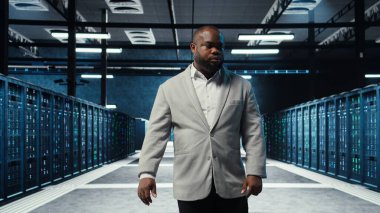 Çalışan veri merkezinde sistem faaliyeti gösteren platformlarda yanıp sönen ışıklarla yürüyor. Bilgi İşlem Uzmanı, loş ışıklandırmalı sunucu çiftliği, düzgün işlemler için düzenlenmiş ekipman, kamera A