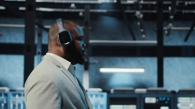 Müzik dinleyen mutlu bir yönetici, veri merkezinde sistem faaliyeti gösteren yanıp sönen ışıklarla yürüyor. Neşeli adam kulaklık takıyor. Sunucu çiftliği, kamera B 'yi denetliyor.