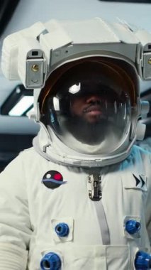 Dikey video bilimci miğfer takıyor son teknoloji uzay gemisinde yürüyor, güneş sisteminde kozmik yolculuk yapıyor. Yörünge istasyonunda kozmonot kıyafeti giyen Afrikalı Amerikalı astronot, kamera B