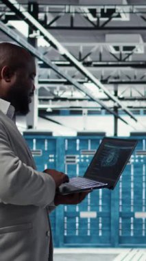 Yapay zeka algoritmaları geliştirmek için tablet kullanan dikey video Veri Merkezi yazılım geliştiricisi. Sunucu merkezindeki programcı dizüstü bilgisayarını kullanarak, sunucudaki sunucuları destekleyen veritabanlarını koruyor