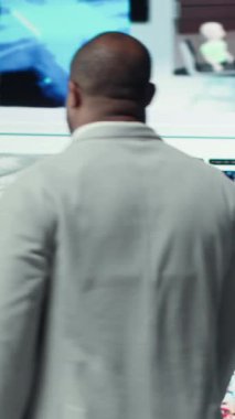 Dikey video, kolları açık, büyük dijital video duvarına bakan, sonsuz eğlence seçiminden yararlanarak mutluluğu ifade eden aşırı neşeli bir adam. Neşeli izleyiciler sonsuz akışa erişmenin keyfini çıkarıyor