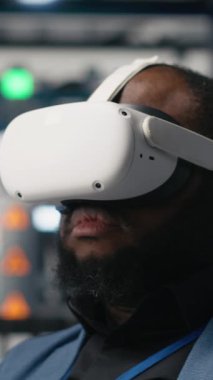 Dikey Video Siyah fotovoltaik fabrikası uzmanı, güneş panellerini yerleştirmek için robotik kollarla çalışan dijital güneş pillerini monte etmek için VR gözlükleri kullanır. Mühendis sanal gerçeklikte makineler kullanır.