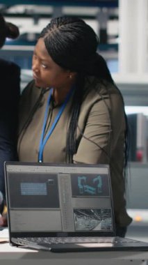 Dikey Video Afrikalı Amerikalı teknisyenler güneş panellerini güneş enerjisi altyapısı için takım çalışmasını ve sürdürülebilirliği yansıtan bir imalat tesisinde inceliyor. Temiz enerjiye duyarlılık. Kamera B