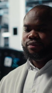 Dikey görüntülü gülümseyen sunucu odası mühendisi dizüstü bilgisayardaki yazılımı kullanarak sunucu raflarında bakım yapıyor. Happy data center IT profesyonel bıçaklı sunucu bileşenlerini dizüstü bilgisayar ve kamera kullanarak güncelliyor