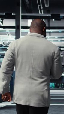 Sistem istikrarı için yazılım güncellemelerini yönetmek için dizüstü bilgisayar kullanan dikey video veri merkezi teknisyeni. Afro-Amerikan sunucu odası IT profesyonel performansı optimize ediyor, altyapıyı yapılandırıyor