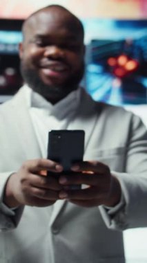 Telefondaki gülümseyen kişinin videosu, internet içeriğiyle boş zamanların tadını çıkarıyor. Neşeli bir adam dijital arkaplan önünde akıllı telefondan sosyal medya uygulamasına göz atıyor.