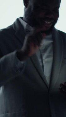 Dikey video Mutlu insan telefonda dokunmatik ekranda yazarak rahatlıyor, şekillendirilmiş dijital içerikle. Modern ortamdaki etkileşimli gösterge paneli önünde akıllı telefondan sosyal medya uygulamalarına bakan neşeli bir adam