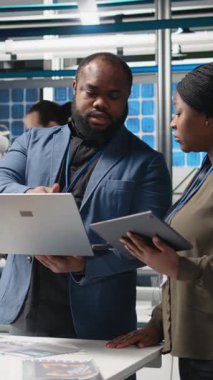 Dikey Video Afrikalı Amerikalı iş ortakları mühendisler güneş enerjisi üretim tesisinde toplanarak yenilenebilir enerji ve endüstriyel operasyonlarda gelecekteki gelişmeleri planlıyorlar. Kamera.