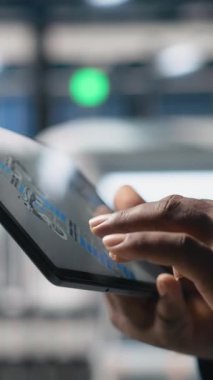 Dikey Video Sanayi Uzmanı tablet üzerindeki dijital imalat sistemlerini, fabrikadaki güneş enerjisi üretim hattını kontrol ediyor. Siyahi uzmanlar güneş santralinde endüstri mühendisliği gösteriyor. Kapat.