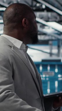 Sistem istikrarını yükseltmek için dizüstü bilgisayar kullanarak gülen dikey video veri merkezi programcısı. Neşeli Afro-Amerikan sunucu merkezi bilişim uzmanı kodlama, cihaz ile performansı optimize etme, ayarlama ekipmanları, kamera