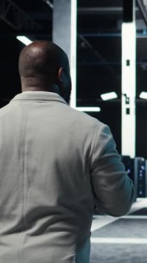 Dikey video sunucu odası yazılım geliştiricisi dizüstü bilgisayardaki yazılımı kullanarak sorun yaratma hatası. Afrika kökenli Amerikalı bilişim uzmanı veri merkezinde yürüyor. Not defteri, kamera A kullanarak hata düzeltme yapıyor.