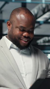 Dikey video mühendisi veri merkezinde yürüyor daha hızlı işlemek için tablet üzerindeki algoritmaları inceliyor. Altyapı kaynak optimizasyonu için sunucu çiftliği kodları yazan neşeli bir çalışan