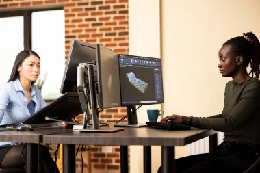 Afrika kökenli Amerikalı geliştirici bilgisayardaki teknik CAD yazılımını kullanarak 3 boyutlu makine ekipmanı tasarlıyor. Çok ırklı kadın mühendisler yaratıcı ajans ofisinde oturmuş çeşitli projeler üzerinde çalışıyorlardı..