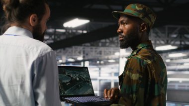 Sunucu odasındaki asker acil operasyonlar sırasında tahliye için coğrafi verileri kullanıyor. Üniformalı askeri veri merkezi personeli, laptop kullanarak afet müdahale lojistiğini koordine ediyor.