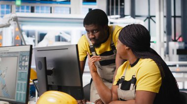 Yüksek teknolojili bir güneş paneli fabrikasında çalışan siyah mühendislik ekibi, dinlenme süresini ve kusursuz üretim sürecini azaltıyor. Teknisyenler güneş enerjisi üretimini optimize ediyorlar. Kamera A.