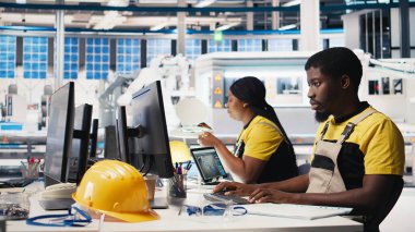 Afrika kökenli Amerikalı denetçi ofisteki enerji kontrol sistemlerini inceliyor, güneş enerjisi üretim teknolojisiyle çevrili. Erkek mühendis güneş enerjisi ve üretimi dengeler. Kamera B.